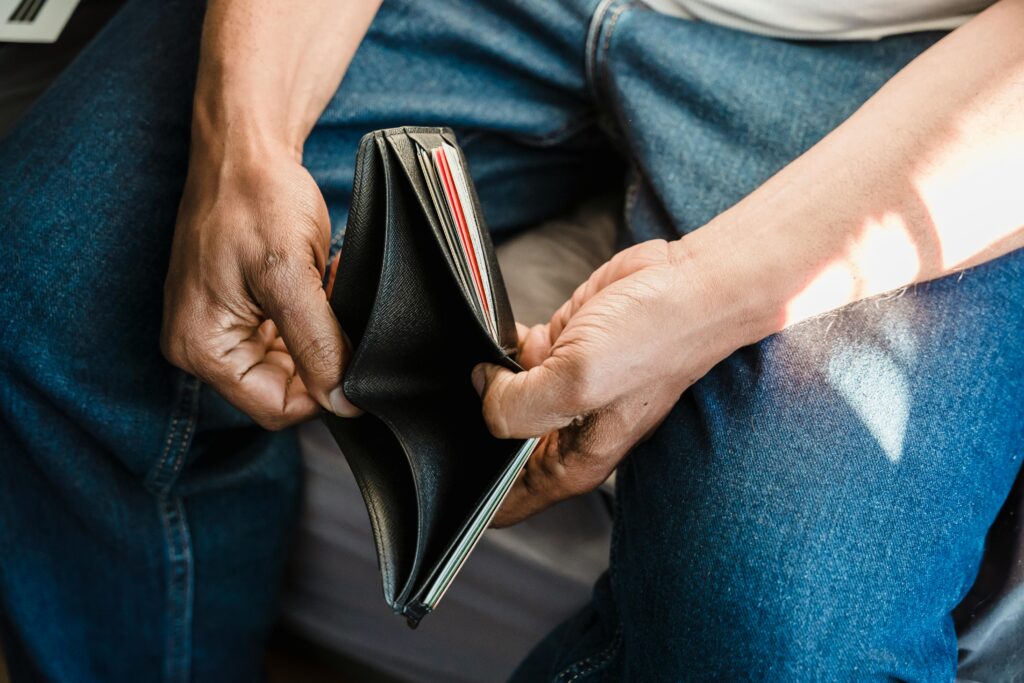 Close-up of a man holding an empty wallet, symbolizing financial crisis and hardship.